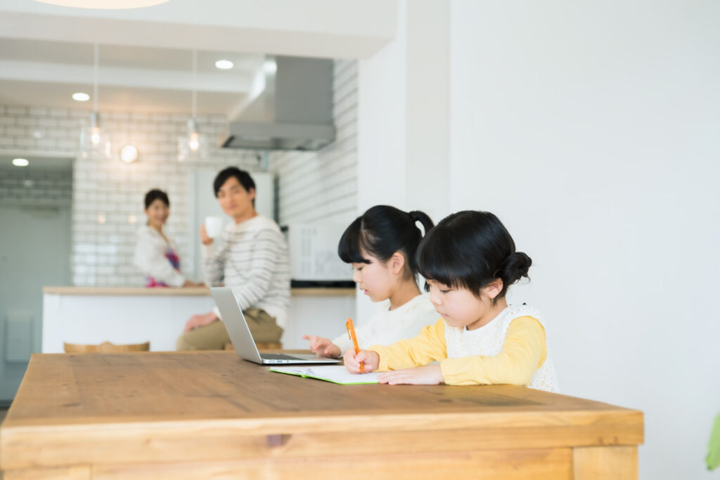 学習する女の子2人と両親